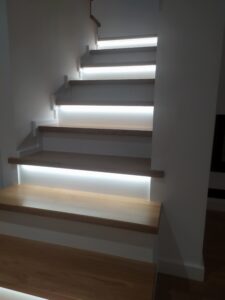 Dębowe schody z białą podstopnicą i oświetleniem Led. Wykończenie olejowosk w kolorze surowego drewna. Realizacja schody Poznań